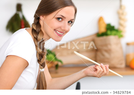 Young woman is cooking in a kitchen. Housewife is 34829784