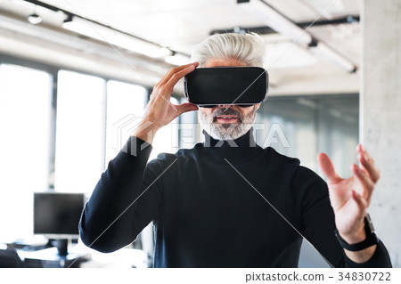 Mature businessman with VD goggles in the office. Mature businessman with VD goggles in the office. 34830722