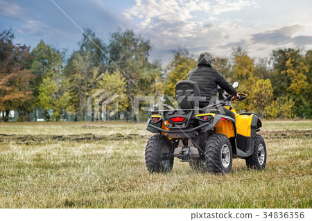 Racer on yellow ATV leaving into the distance Racer on yellow ATV leaving into the distance 34836356