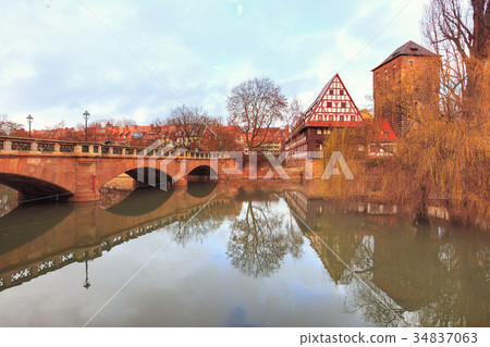Old buildings and bridge reflected in water 34837063