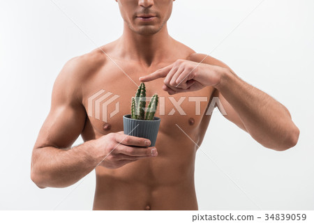 Youthful man is demonstrating prickly houseplant 34839059