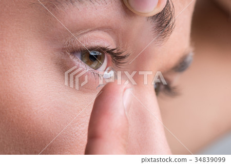 Pleasant youthful guy is using optic component 34839099