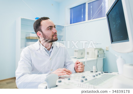 handsome doctor using an ultrasound machine 34839178
