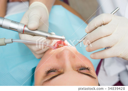 Hands of dentist curing a female patient with Hands of dentist curing a female patient with 34839428