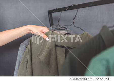 Girl choosing coat among few things 34840318