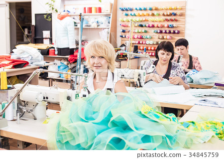 Seamstresses sews dresses in atelier studio. Seamstresses sews dresses in atelier studio. 34845759