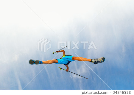 Young man athlete makes a jump with nordic walking sticks Young man athlete makes a jump with nordic walking sticks 34846558