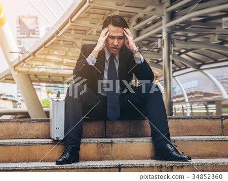 Desperate businessman sitting hopelessly on stair floor 34852360