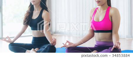 Women doing yoga lotus pose in fitness gym class 34853884