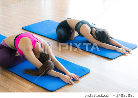 Women doing back stretching yoga in fitness gym 34853885