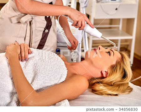 Young woman receiving electric facial massage. 34856830