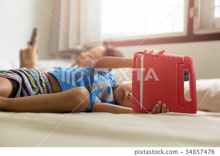 Mother and Son in bed while his playing tablet Mother and Son in bed while his playing tablet 34857476