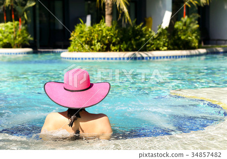 Woman in pink hat relaxing in swimming pool Woman in pink hat relaxing in swimming pool 34857482