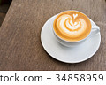 A white cup of coffee latte art on wood table 34858959
