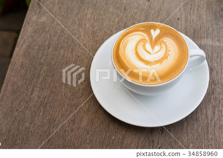 A white cup of coffee latte art on wood table 34858960