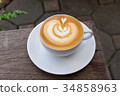 A white cup of coffee latte art on wood table 34858963