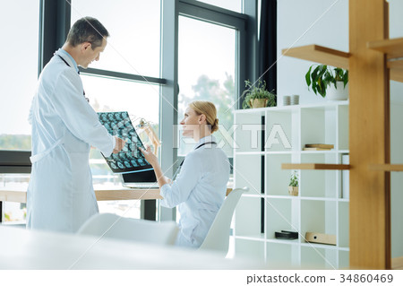 Positive smart doctors discussing an X ray scan Positive smart doctors discussing an X ray scan 34860469