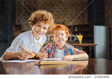 Adorable brother smiling into camera while drawing 34860890