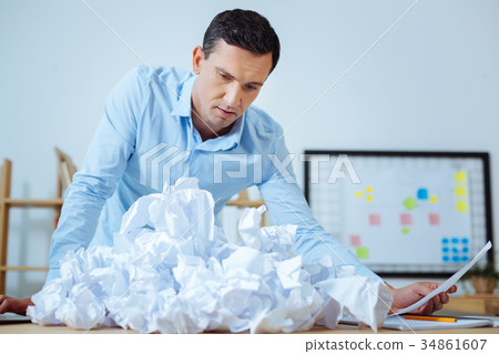 Confused office worker looking at crumpled paper Confused office worker looking at crumpled paper 34861607