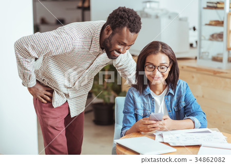 Cheerful man looking at his colleagues phone 34862082