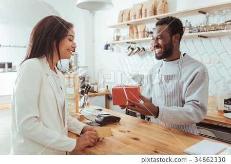 Smiling barista giving his customer a box with Smiling barista giving his customer a box with 34862330
