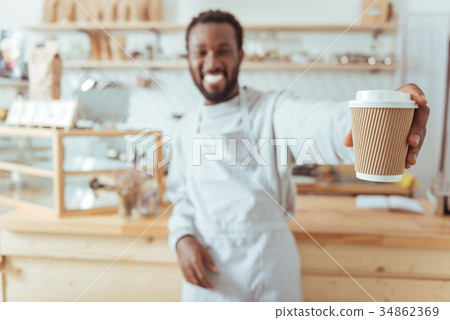Cheerful barista handing a cup of coffee 34862369