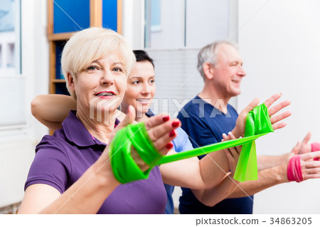 Physio showing senior couple how to use rubber 34863205