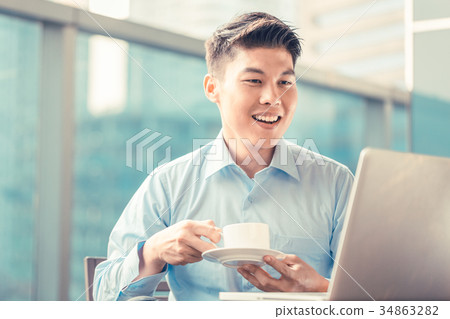 Chinese businessman having coffee at his laptop Chinese businessman having coffee at his laptop 34863282