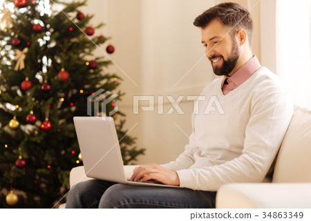 Handsome man working on laptop in room with Handsome man working on laptop in room with 34863349