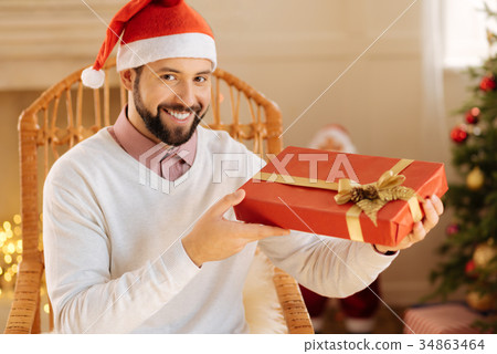 Happy man in Santa hat posing with gift box Happy man in Santa hat posing with gift box 34863464