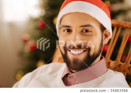 Happy man in Santa hat posing in rocking chair Happy man in Santa hat posing in rocking chair 34863486