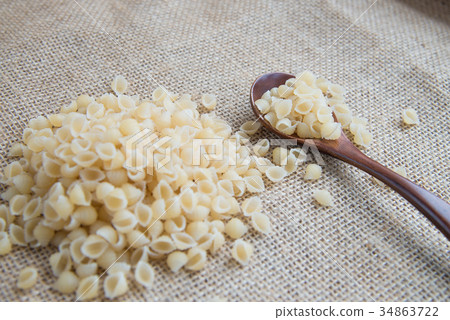 Raw pasta in wooden spoon on sack rustic 34863722