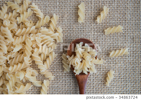 Raw pasta in wooden spoon on sack rustic 34863724
