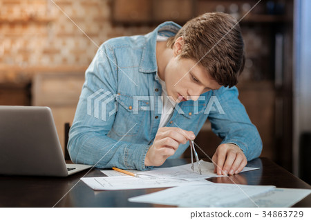 Young man drawing blueprint with a pair of 34863729