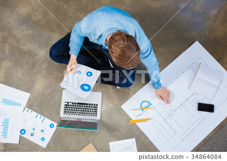 Top view of engineer studying charts and blueprint 34864084