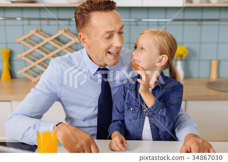 Positive blonde girl giving a cookie to her dad Positive blonde girl giving a cookie to her dad 34867030