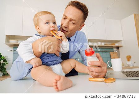 Delighted cute girl putting a bagel into her mouth 34867718