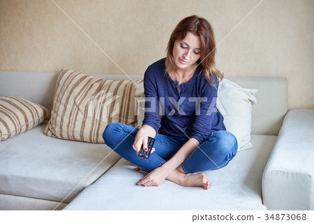 Beautiful young woman watching tv on sofa at home Beautiful young woman watching tv on sofa at home 34873068