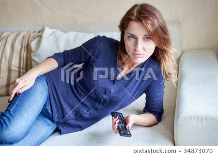 Beautiful young woman watching tv on sofa at home Beautiful young woman watching tv on sofa at home 34873070