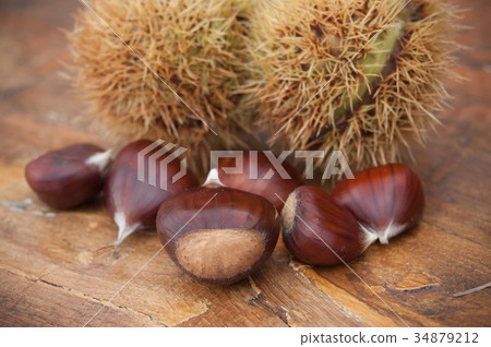 closeup of chestnuts on wooden bench background closeup of chestnuts on wooden bench background 34879212
