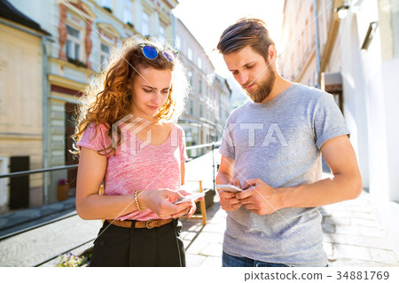 Young couple with smartphones on the street. 34881769