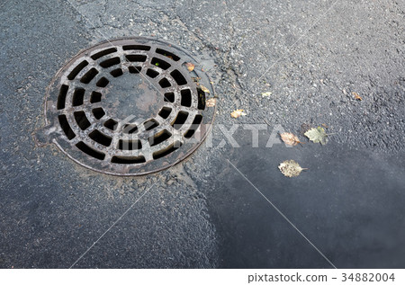 Round sewer manhole cover in asphalt street Round sewer manhole cover in asphalt street 34882004