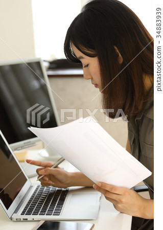 Woman checking while looking at PC and documents 34883939