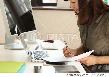 Woman checking while looking at PC and documents 34883940