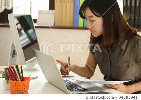Woman checking while looking at PC and documents 34883941