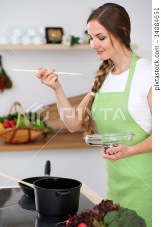 Young woman is cooking in a kitchen. Housewife is Young woman is cooking in a kitchen. Housewife is 34884651