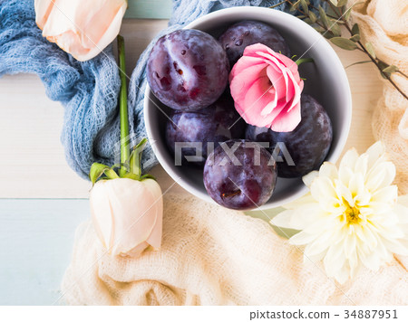 Blue plums in bowl with flowers Blue plums in bowl with flowers 34887951