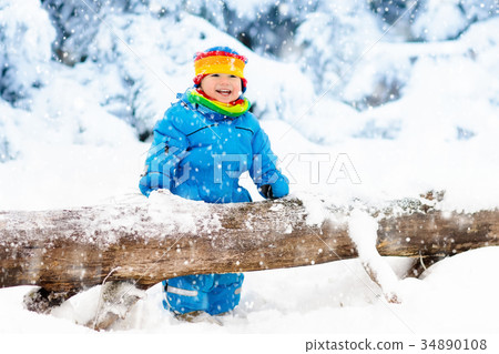 Baby playing with snow in winter. Child in park. 34890108