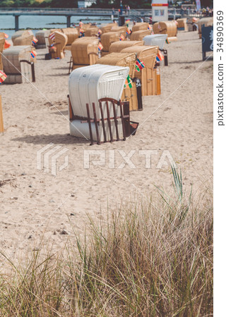 Roofed wooden chairs on sandy sea beach. German Roofed wooden chairs on sandy sea beach. German 34890369