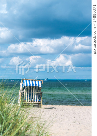Rainy clouds above beach with blue colored roofed 34890371